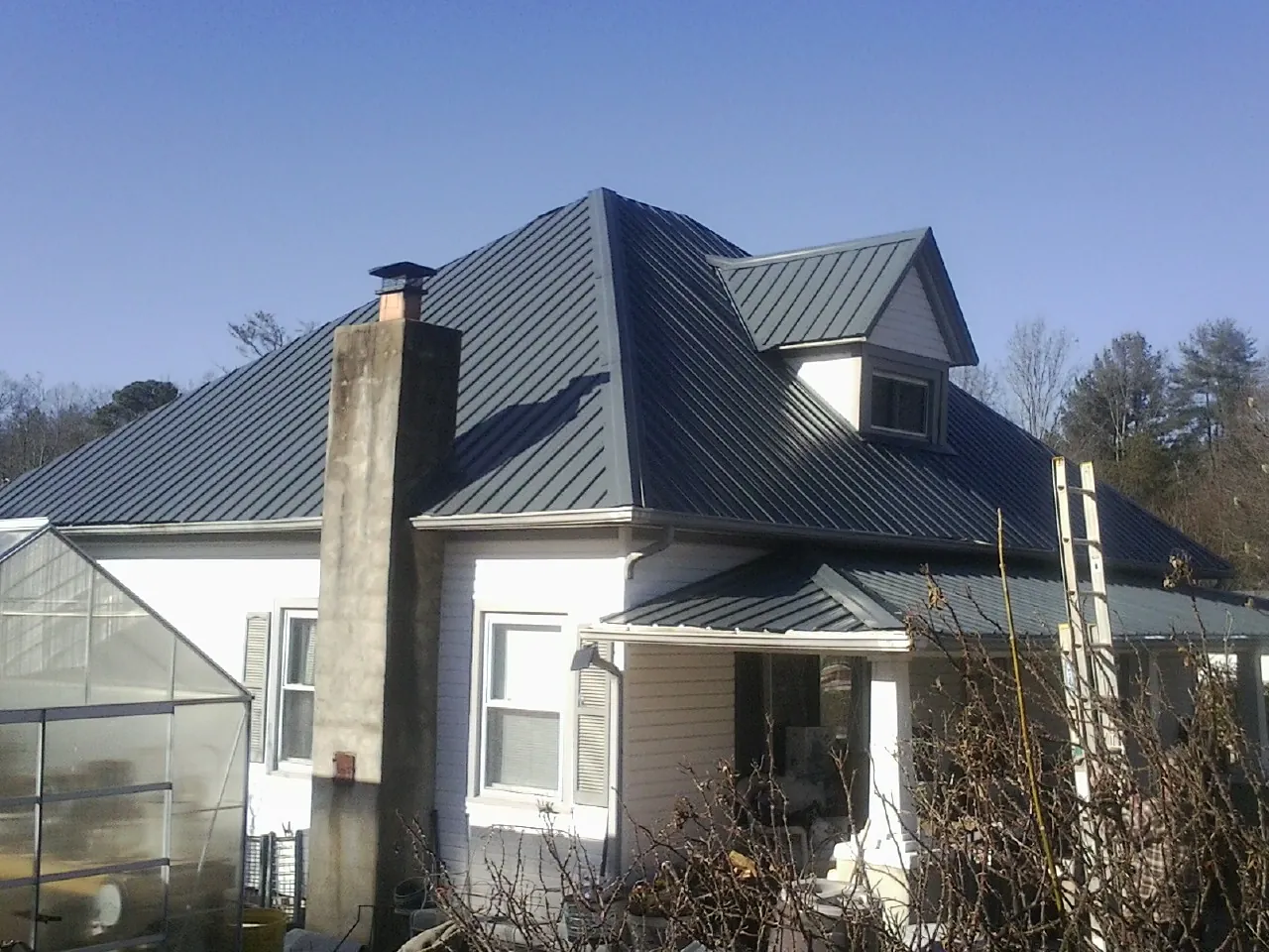 Dark blue standing seam metal roof on a white farmhouse with dormer — Slate & Tile Roof Repair by Roofing Brothers in Lane