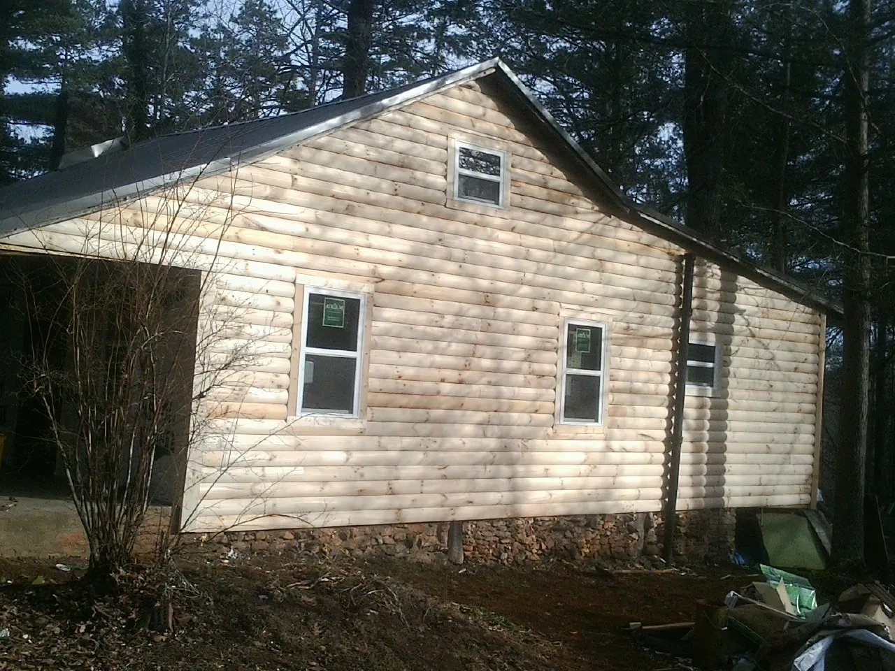 New log siding and dark metal roofing on a gable end in Lane