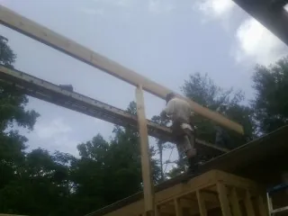 Carpenter setting a ridge beam over a new addition frame — Ice Dam Removal by Roofing Brothers in Lane