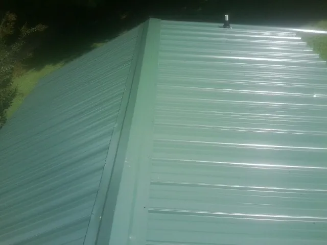 New green metal panels meeting at the ridge of a roof — Flat Roof Repair work by our crew in Lane