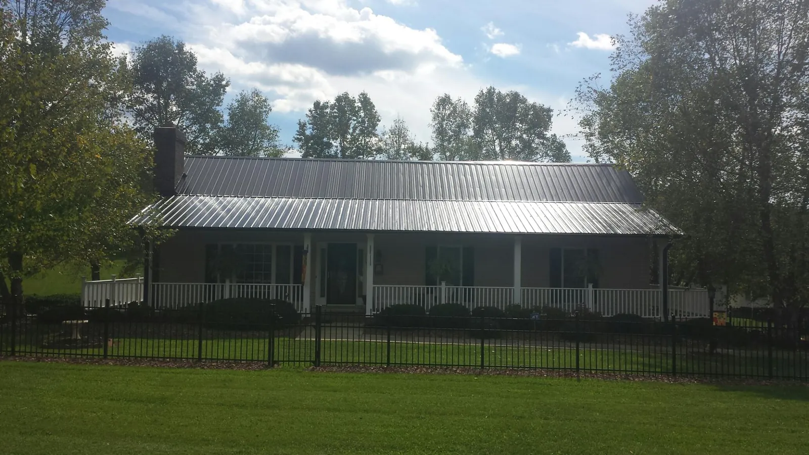 Gray metal roof on a brick ranch with a full width front porch — Gutter Guard Installation work by our crew in Lane